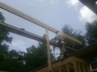 Carpenter setting a ridge beam over a new addition frame — Ice Dam Removal by Roofing Brothers in Cedarhurst