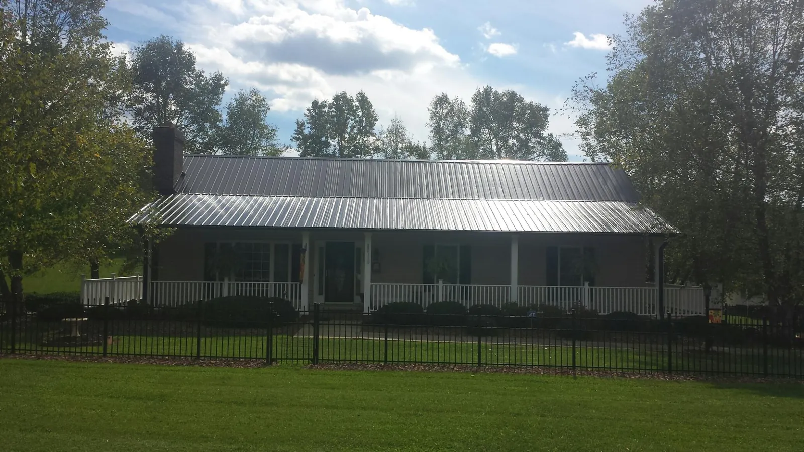 Gray metal roof on a brick ranch with a full width front porch — Gutter Guard Installation work by our crew in Cedarhurst