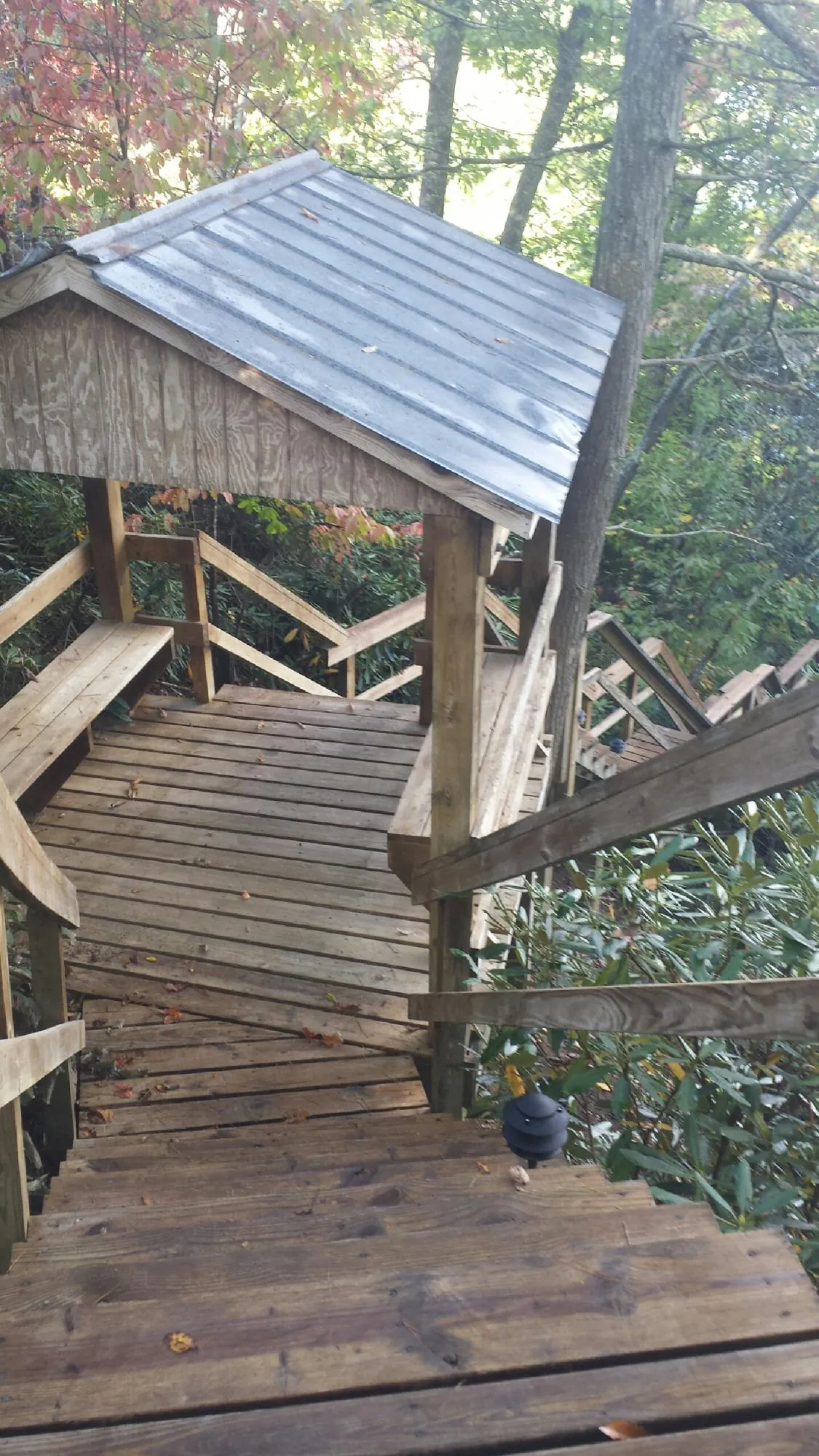 Metal roofed shelter over wooden steps on a wooded walkway — Skylight Repair & Installation work by our crew in Cedarhurst