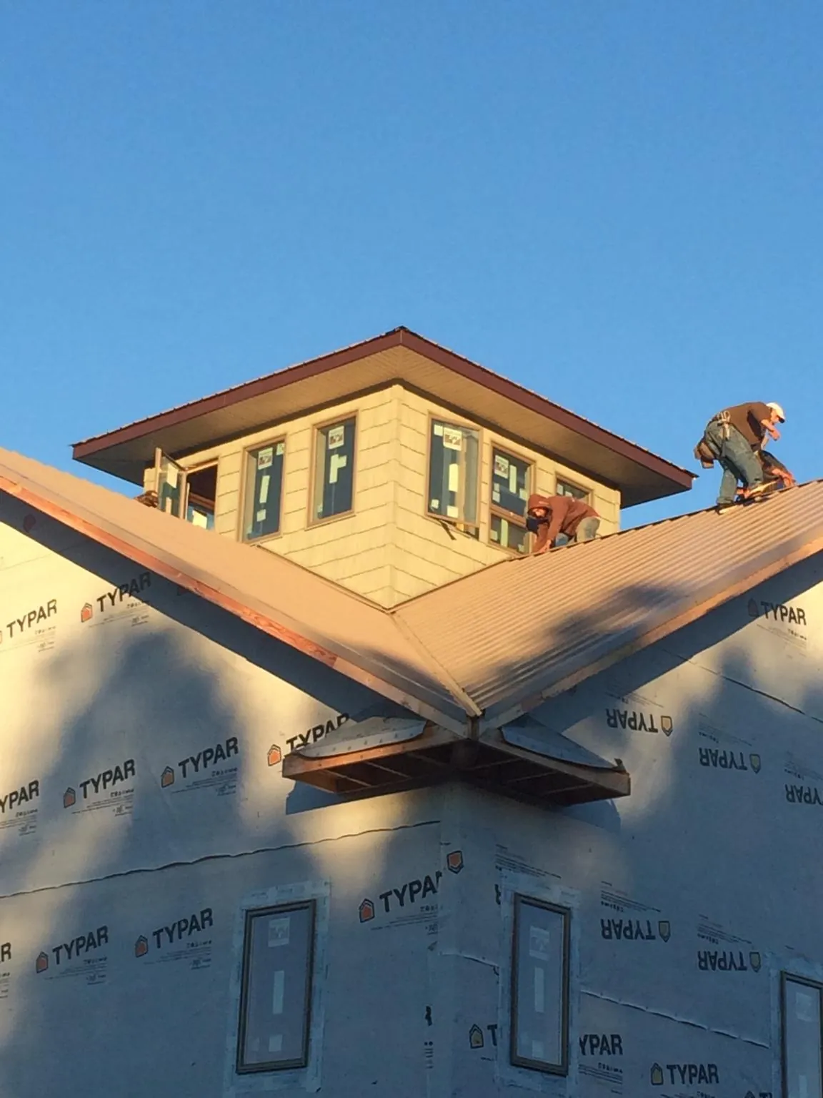 Roofers working around a rooftop cupola on a new metal roof at sunset — Roof Waterproofing in Cedarhurst by Roofing Brothers